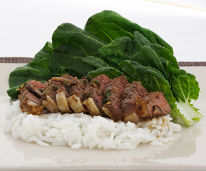 Photo of sliced beef on bed of noodles with steamed spinach.