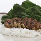 Photo of sliced beef on bed of noodles with steamed spinach.