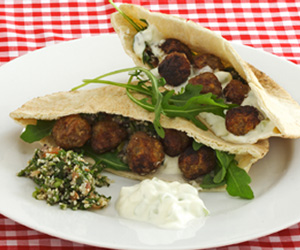 Photo of meatballs in a pitta bread pocket with rocket and tabouleh.