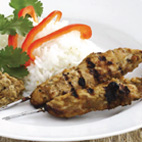 Photo of sate chicken kebabs with rice and red capsicum slices.